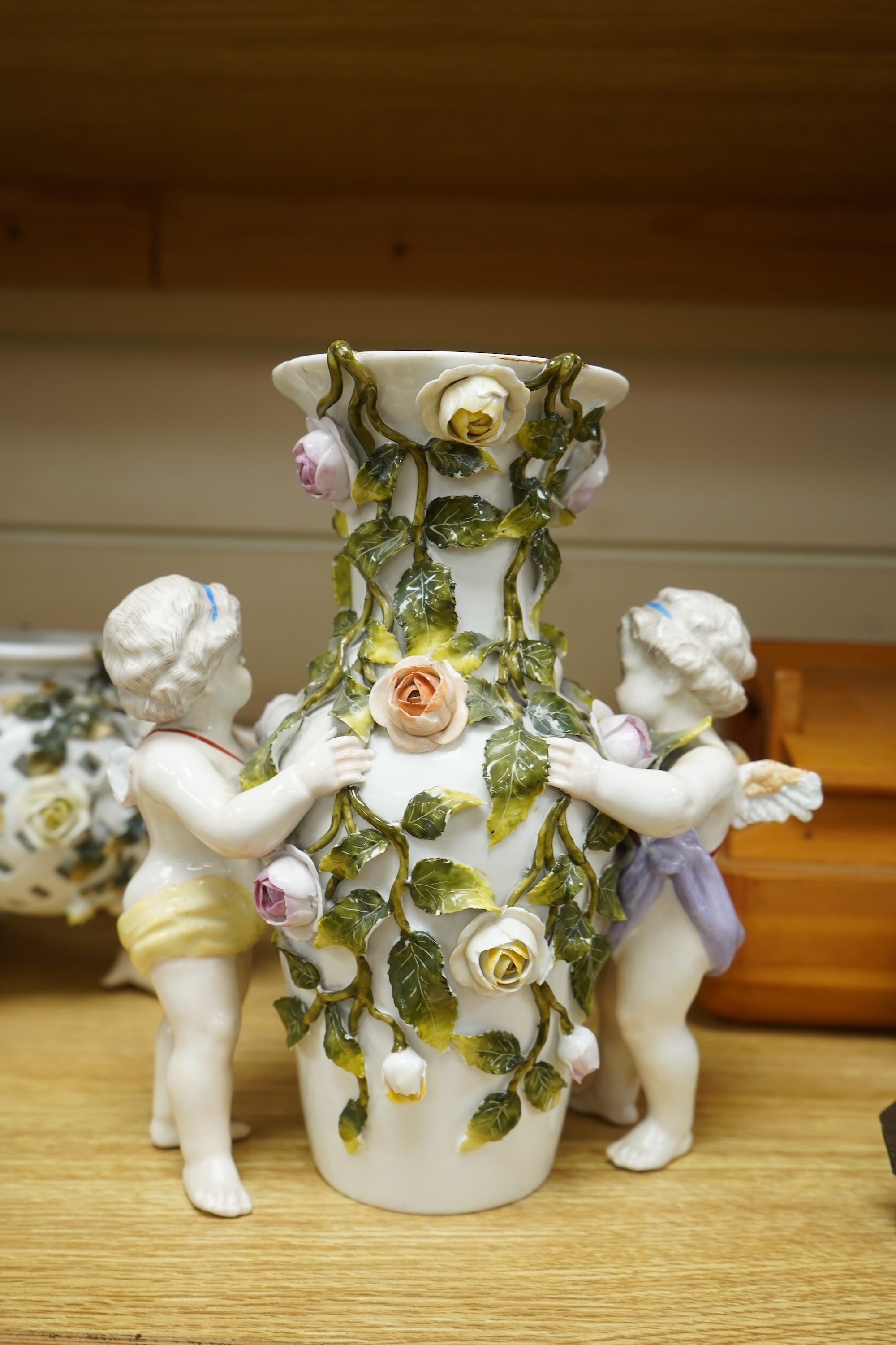 A German flower encrusted porcelain figural candelabrum, 30cm high, a cherub jardiniere and a cherub vase, all encrusted